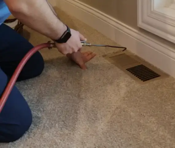 ABD technician cleaning a floor air duct register with a vacuum hose