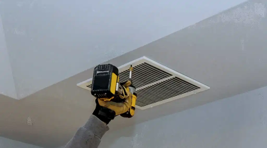 Technician removing a ceiling air vent cover for air duct cleaning in Tysons, VA