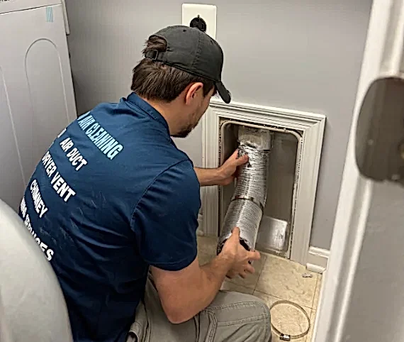 ABD technician in uniform servicing a dryer vent wall connection