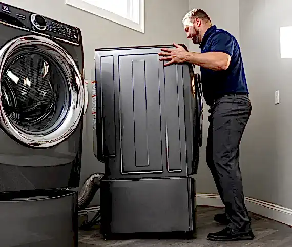 ABD technician pulling a dryer away from the wall to reach the dryer vent in a Fairfax home