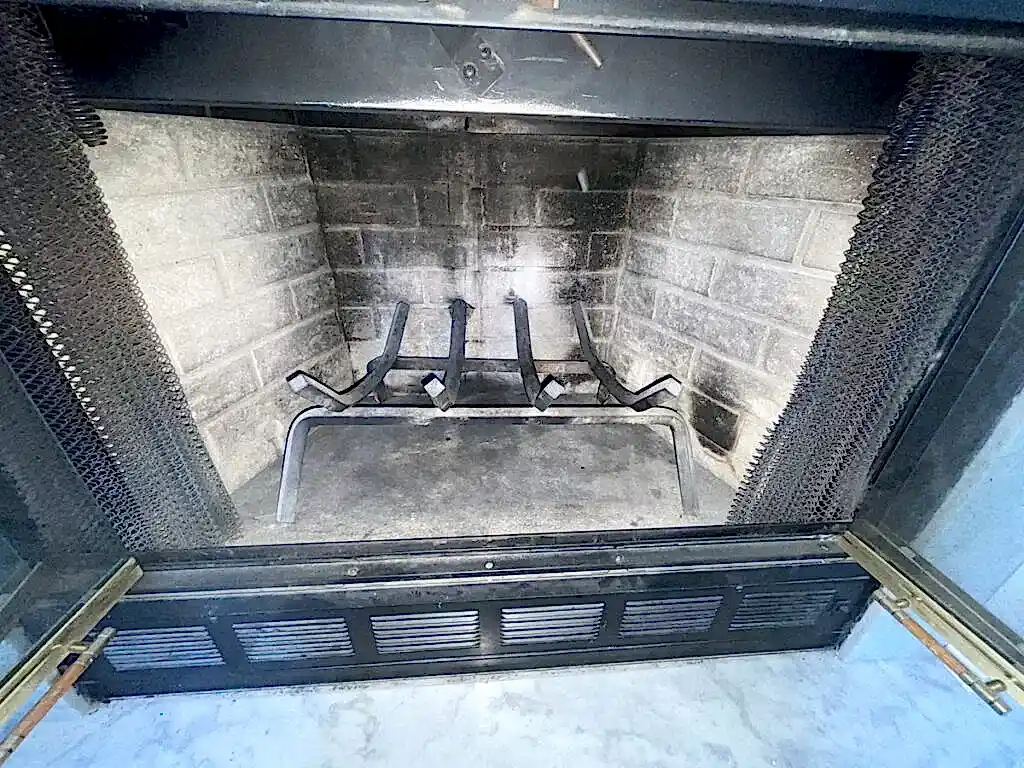 Wood-burning fireplace with the glass doors open during an ABD chimney cleaning visit