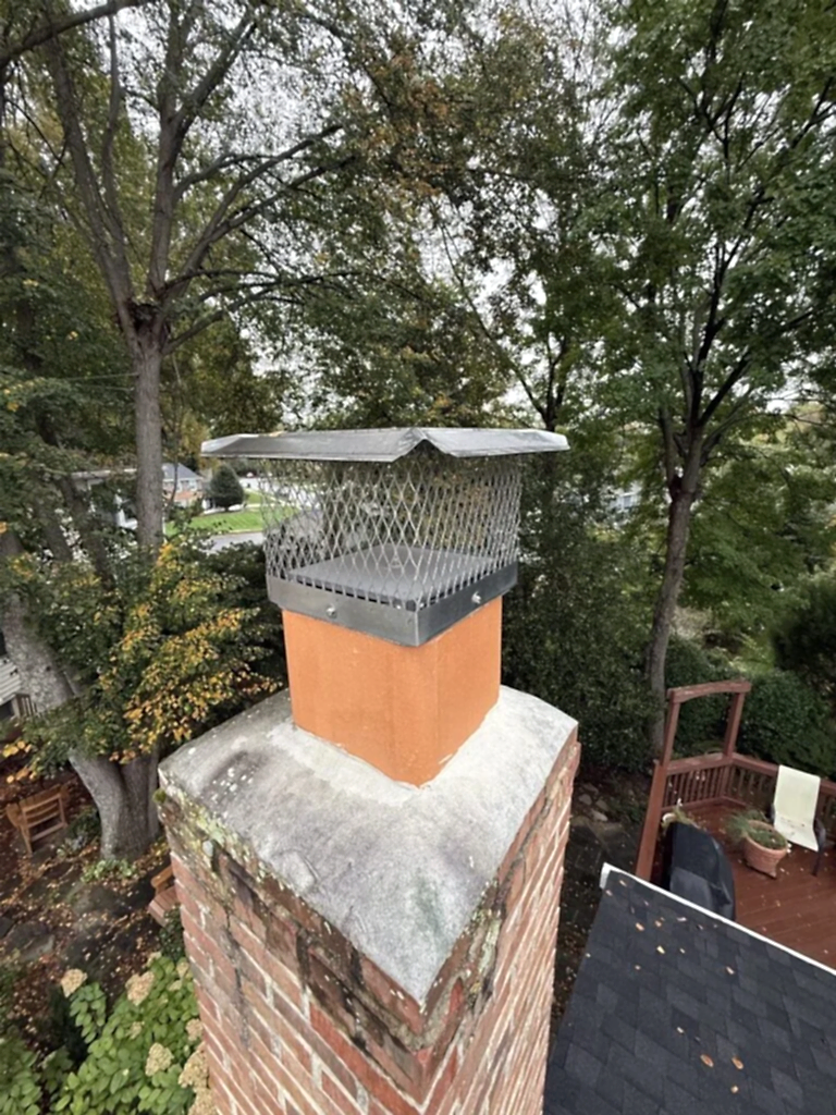 Stainless steel mesh chimney cap on a single clay flue tile on top of a brick chimney
